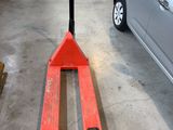 un chariot élévateur dans un garage, avec une voiture en arrière-plan