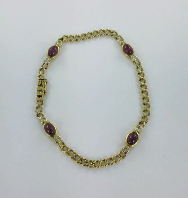 un gros plan d'un bracelet en or orné de pierres violettes