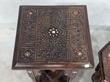 pair of carved wooden side tables with intricate designs on them