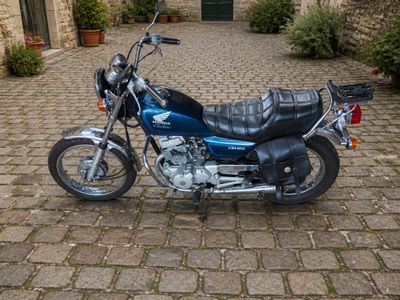une moto bleue garée dans une rue pavée