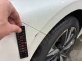 a person holding a remote control in front of a white car