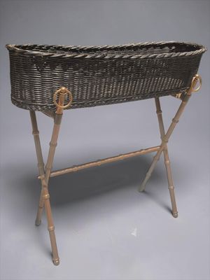 un panier en osier posé sur un support, sur fond gris