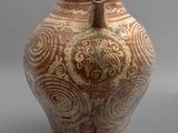 un vase marron et blanc posé sur une surface grise