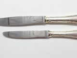 pair of silver plated knifes on a white surface