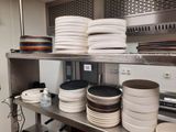de nombreuses assiettes et casseroles empilées sur une étagère dans la cuisine