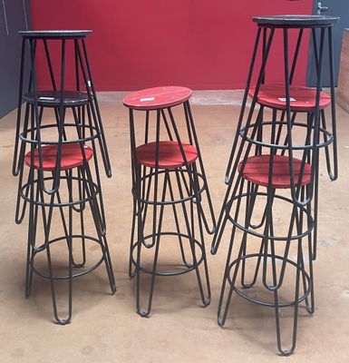 quatre tabourets aux assises rouges sont disposés devant un mur rouge
