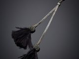 a pair of black feathers hang from a hook on a black background