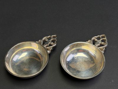 pair of silver plated spoons with chain handles on a black surface