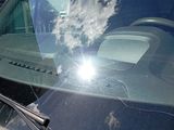 a car that is parked in front of a building with the sun shining through the windshield