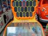 une borne d'arcade orange et jaune dans une pièce remplie de voitures
