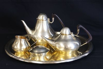 a silver tea set on a silver tray on a black background