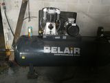 un compresseur d'air noir posé dans un garage, près d'un mur