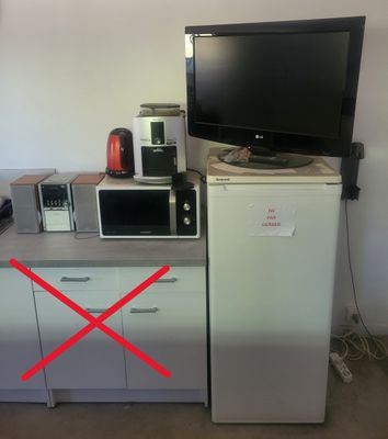 une photo d'une cuisine équipée d'un micro-ondes, d'un réfrigérateur et d'une télévision