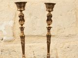 two gold candlesticks sitting on a table in front of a brick wall