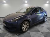 a blue tesla model y parked on a checkered tile floor