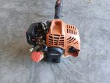 une tondeuse à gazon orange et noire fonctionnant à l'essence, posée sur un sol en béton