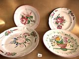 three plates with floral designs are sitting on a gold cloth