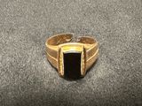 Gros plan sur une bague en or ornée d'une pierre noire