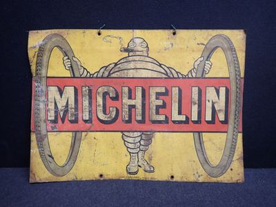 une vieille enseigne en tôle faisant la promotion des pneus Michel sur fond bleu