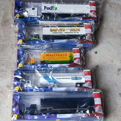 six petits trains en plastique, rangés dans des sachets, alignés sur le sol