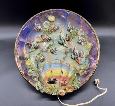 une assiette colorée sur laquelle est posé un éventail, posée sur une table