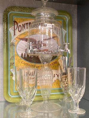 des bouteilles et des verres posés sur une table en verre, avec une pancarte « Ne me faites pas peur » en arrière-plan