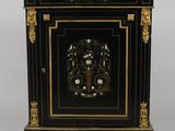 a black and gold painted cabinet with a floral design on the door