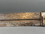 an old knife with a gold handle sitting on top of a table