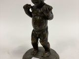 une figurine antique en bronze représentant un garçon tenant un gant de baseball