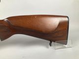a wooden rifle on a clear acrylic stand on a white background