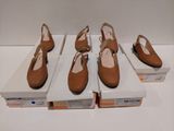 quatre paires de chaussures pour femmes dans leurs boîtes, posées sur une surface blanche