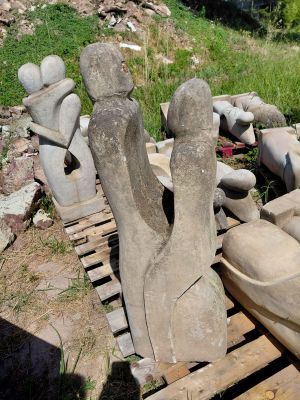 un tas de statues en pierre posées sur une palette dans la cour