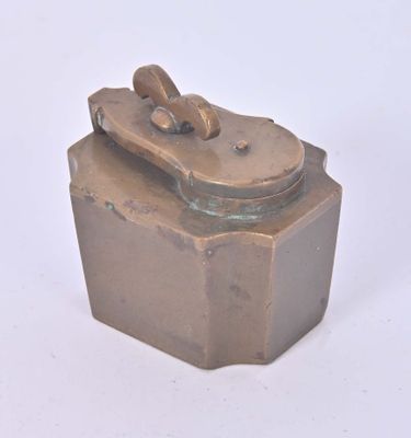 une petite boîte métallique munie d'un couvercle, posée sur une surface blanche