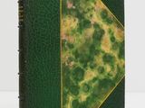 an old book with a green cover and gold trim