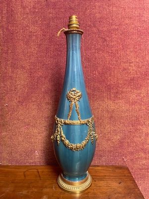 un vase bleu posé sur une table en bois, avec un mur rouge en arrière-plan