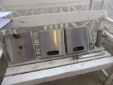 un banc blanc sur lequel sont posées trois poubelles argentées