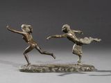 two bronze statues of a man and a woman playing with a frisbee