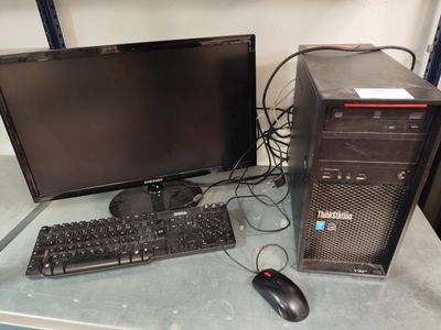 un ordinateur de bureau posé sur une table à côté d'un clavier et d'une souris