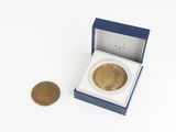 une petite pièce d'or dans une boîte bleue, à côté d'un penny