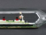 un petit bateau dans une bouteille en verre posée sur une table
