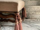 a bench with tassels on it sitting on a marble floor