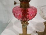 une lampe en verre rose et un bougeoir doré posés sur une table blanche