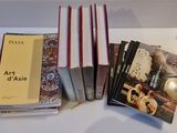 several books are stacked on a table next to a lamp