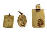 un gros plan sur trois pendentifs en or sur fond blanc