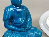 a blue buddha statue next to a plate with a white plate
