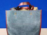 a blue bag with a leather handle on a table