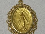 La médaille d'or de la Vierge de Guadalupe est exposée sur un fond blanc.