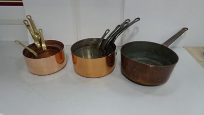Plusieurs casseroles et poêles sont alignées sur un plan de travail