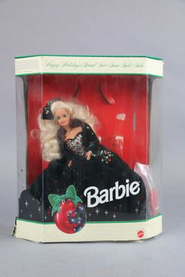 barbie doll in a plastic box with a black dress and a red berry