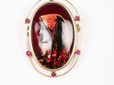 une photo représentant une broche à l'effigie d'une femme portant un chapeau rouge